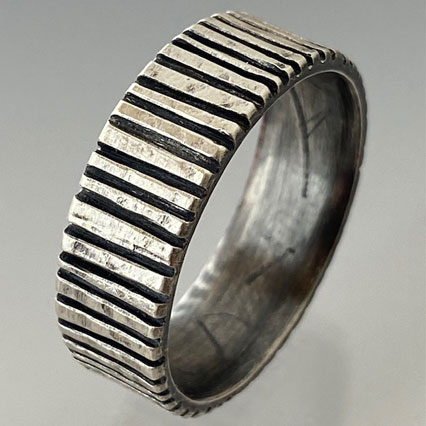 silver ring with low cut areas that are dark